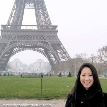A lady stands in front of the Eiffel tower in Paris, France to show audiences how tall is the Eiffel Tower