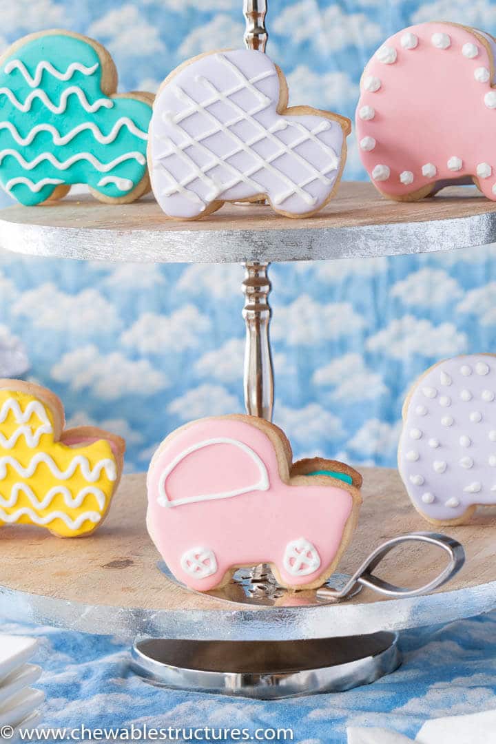 baby shower cookies shaped like baby carriages displayed on a two tier serving tray.