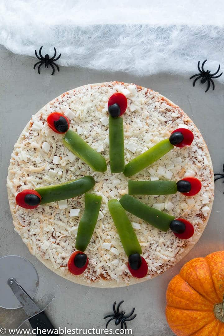 Uncooked whole Halloween pizza on a baking sheet.