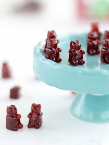 cherry gummy bears sitting on a cupcake stand and on a table