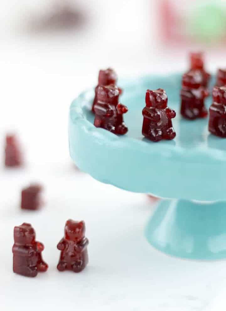 cherry gummy bears sitting on a cupcake stand and on a table