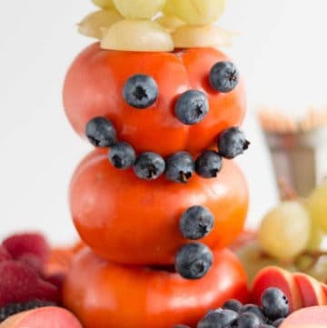 snowman made of persimmon, blueberries, green grapes