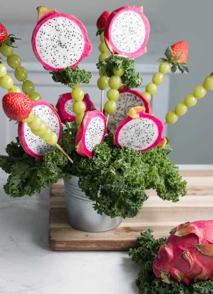 dragon fruit bouquet made of dragon fruit, green grapes, and strawberries on a table