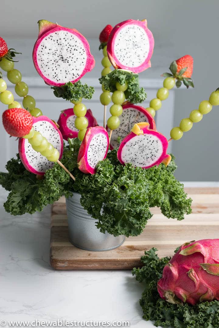 dragon fruit bouquet made of dragon fruit, green grapes, and strawberries on a table
