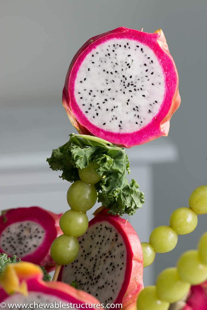 closeup of a dragon fruit slice on a skewer with kale and green grapes