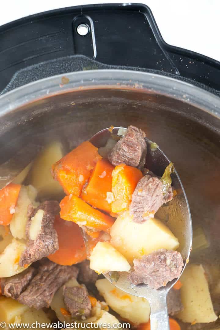 large spoon holding cooked beef stew over the instant pot