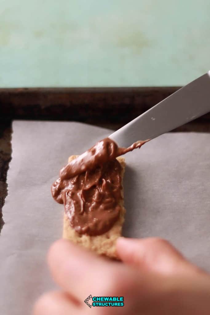 icing spatula spreading melted Toblerone on graham cracker